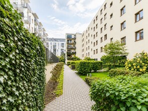 Un edificio residencial con un sendero pavimentado, vegetación y varias ventanas.
