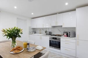 Una cocina moderna con armarios blancos, encimera de mármol y electrodomésticos de acero inoxidable.