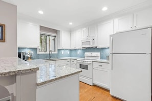 A modern kitchen with white cabinets, a granite countertop, a built-in oven, and a microwave. - Anchor Down - 2 Bed Beach Fun Dining Golf (Seabrook Island)