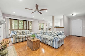 A spacious living room with a large sectional sofa, a coffee table, and a ceiling fan. - Anchor Down - 2 Bed Beach Fun Dining Golf (Seabrook Island)