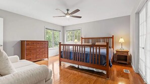 A bedroom with a wooden bed, a dresser, a chair, and a ceiling fan. - Anchor Down - 2 Bed Beach Fun Dining Golf (Seabrook Island)