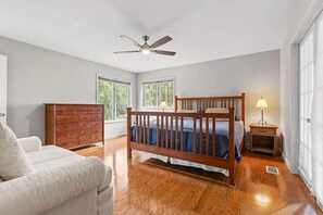 A bedroom with a wooden bed, a dresser, a chair, and a ceiling fan. - Anchor Down - 2 Bed Beach Fun Dining Golf (Seabrook Island)