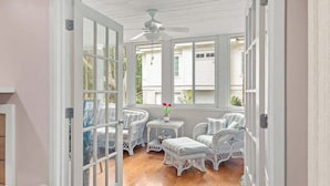 A sunroom with white wicker furniture, a ceiling fan, and a view of the outside. - Anchor Down - 2 Bed Beach Fun Dining Golf (Seabrook Island)