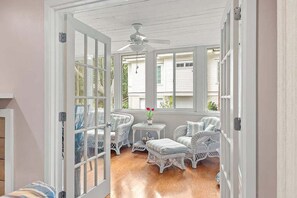 A sunroom with white wicker furniture, a ceiling fan, and a view of the outside. - Anchor Down - 2 Bed Beach Fun Dining Golf (Seabrook Island)