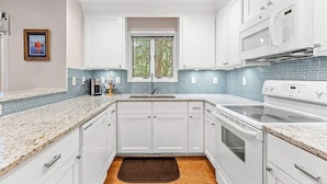 A modern kitchen with white cabinets, a double sink, and a microwave. - Anchor Down - 2 Bed Beach Fun Dining Golf (Seabrook Island)
