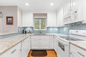A modern kitchen with white cabinets, a double sink, and a microwave. - Anchor Down - 2 Bed Beach Fun Dining Golf (Seabrook Island)