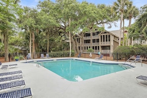 A pool area with lounge chairs and a two-story building in the background. - Anchor Down - 2 Bed Beach Fun Dining Golf (Seabrook Island)
