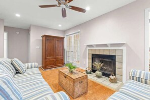 Una sala de estar con un conjunto de sofá, un aparador de madera, una chimenea y un ventilador de techo.