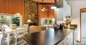 Una cocina con pared de piedra, techo de madera y una isla grande con fregadero.