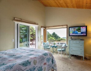 Ein Schlafzimmer mit einem Bett, einem Fernseher, einem Schminktisch und Blick ins Freie.