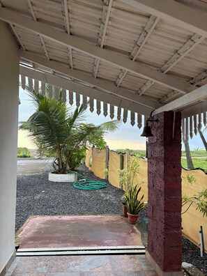 Un espacio al aire libre techado con piso de grava, plantas en macetas y vistas del paisaje circundante.