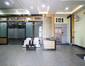 A reception area with a reception desk, seating area, and a wall-mounted elevator.
