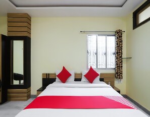 Une chambre d’hôtel avec un lit, une fenêtre avec des rideaux, une table de chevet et un miroir.