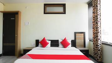 A hotel room with a bed, a nightstand, a mirror, and a window with curtains.