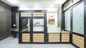 A reception area with a closed door labeled 'OFFICE,' a tiled floor, and a wall with a patterned design.