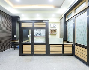 A reception area with a closed door marked 'OFFICE,' a counter with a patterned backdrop, and a wall with a tree design. - Classic Akhand Param (Begusarai)