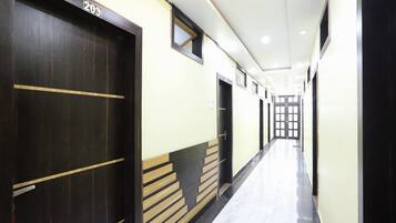 A hallway with doors marked with numbers, a tiled floor, and a light-colored wall.