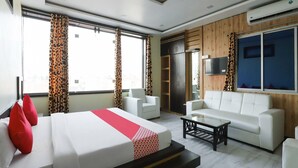 A hotel room with a bed, a sofa, a coffee table, and a TV.
