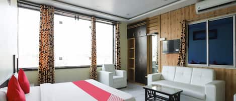 Una habitación de hotel con cama, sofá, mesa de centro y televisor.