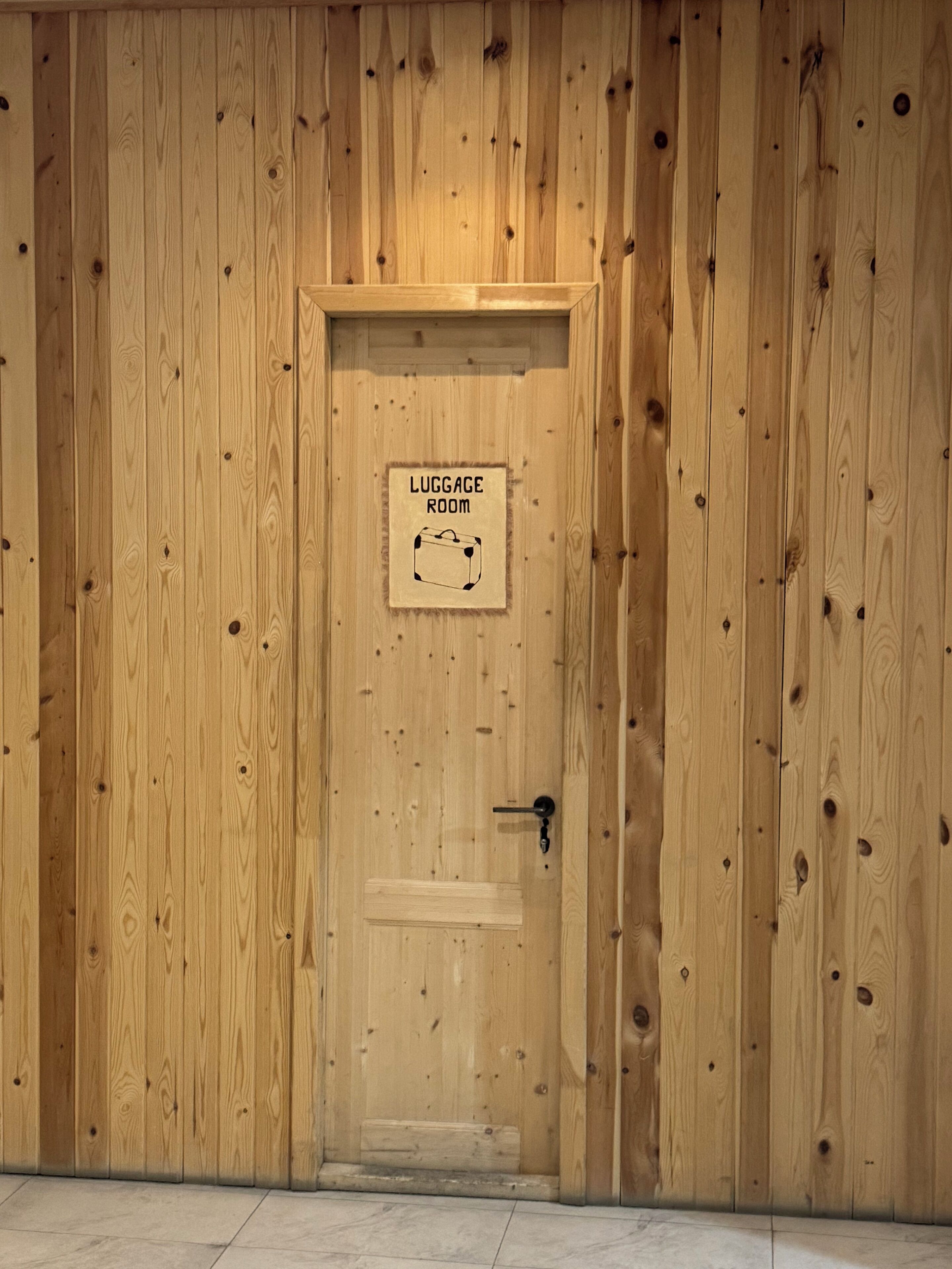 A wooden door with a sign indicating a luggage room.