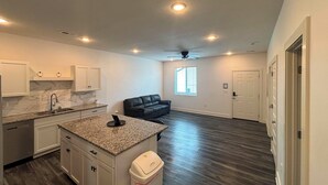 A modern kitchen with granite countertops, white cabinets, and a built-in dishwasher. - Newly Built Condo, 6 Mi to Downtown Wichita! (Wichita)