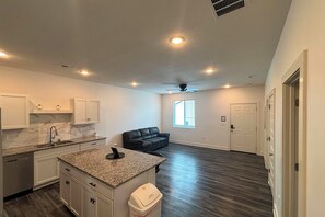 A modern kitchen with granite countertops, white cabinets, and a built-in dishwasher. - Newly Built Condo, 6 Mi to Downtown Wichita! (Wichita)