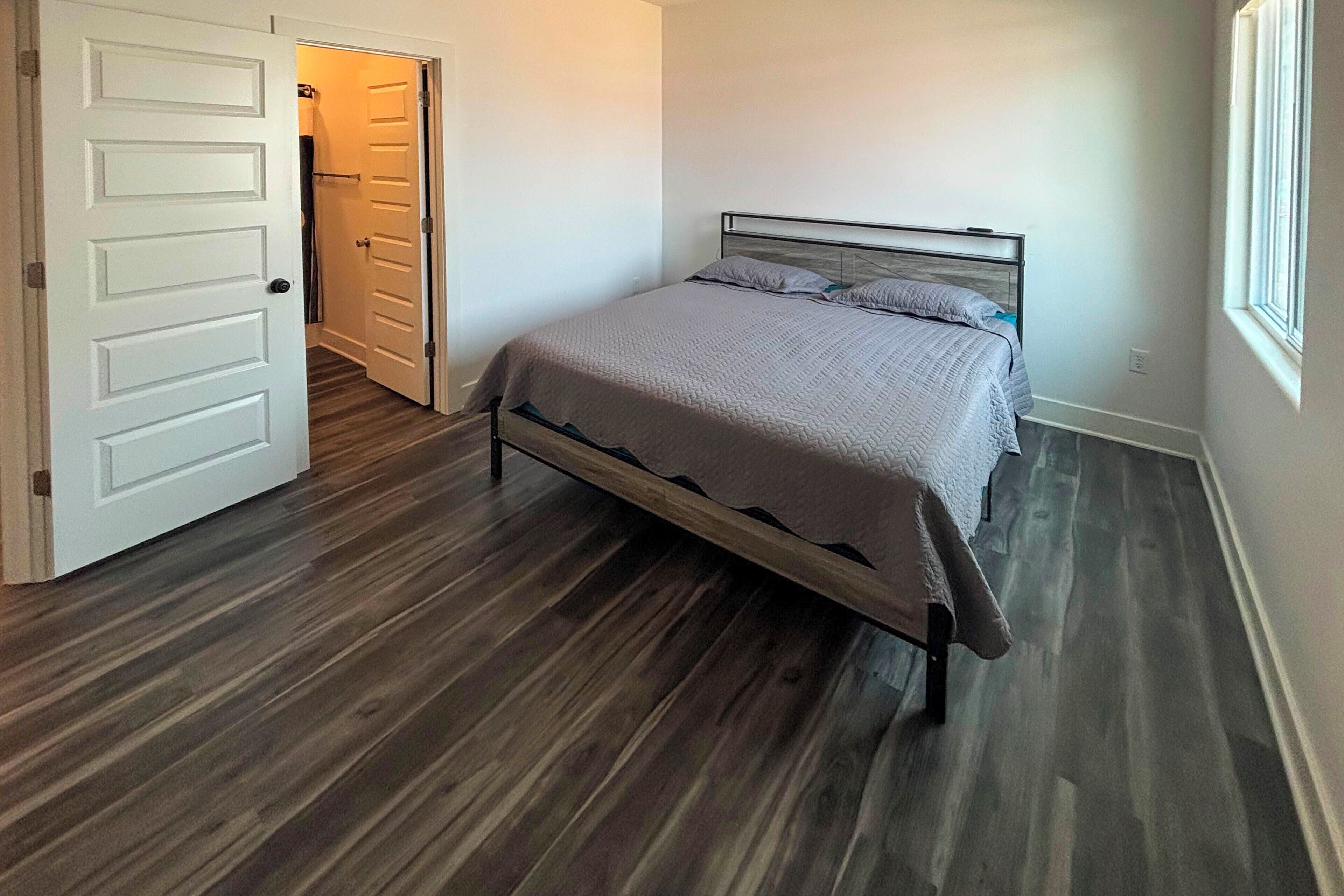 A bedroom with a bed, a door, and a window.
