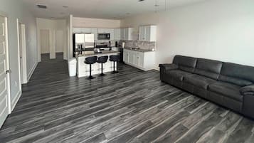 A modern apartment with a kitchen, dining area, and a living room with a sofa.
