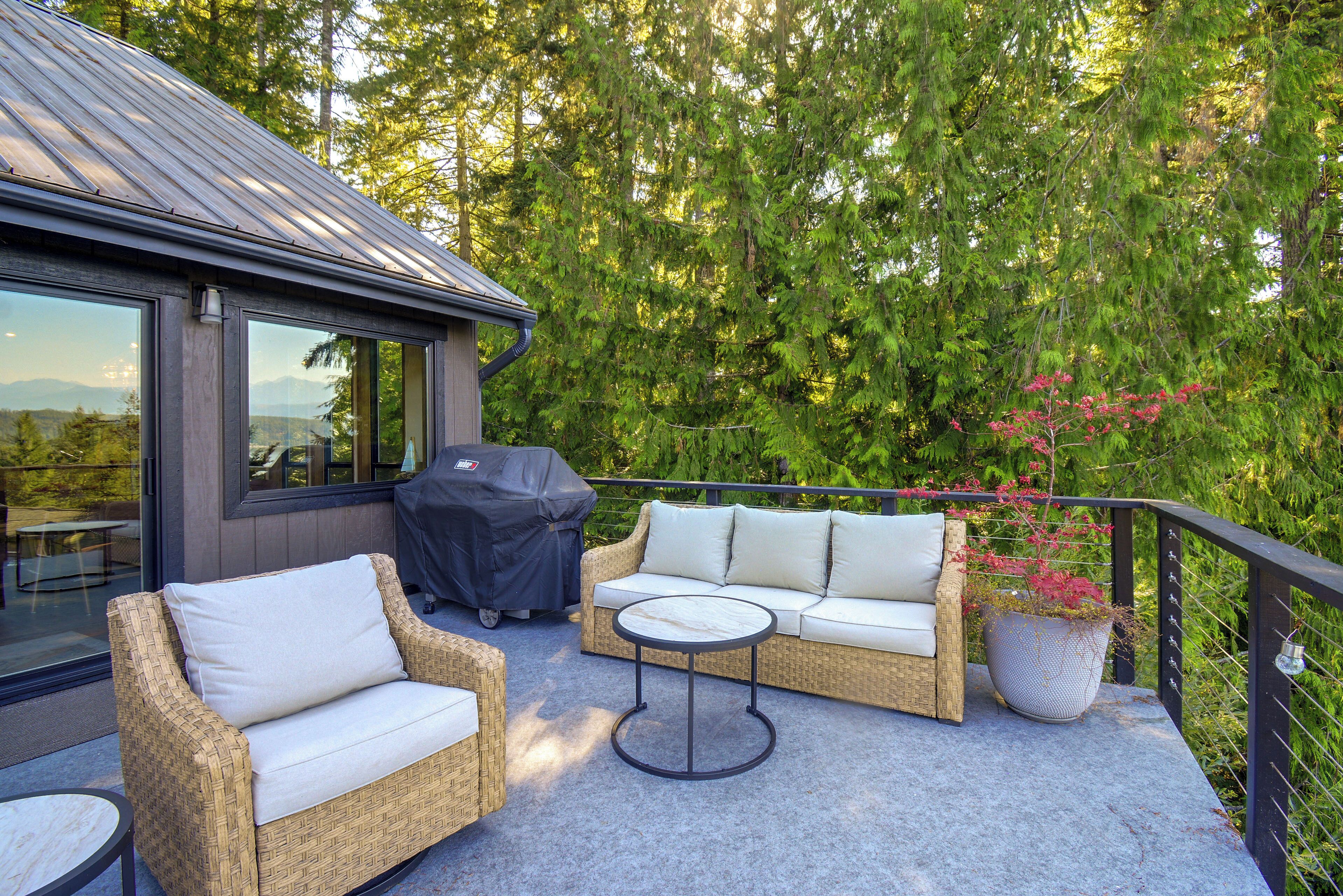 A covered outdoor seating area with wicker furniture and a barbecue grill.