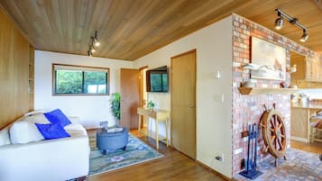 A spacious living area with a white sofa, a coffee table, and a fireplace with a wooden wheel.