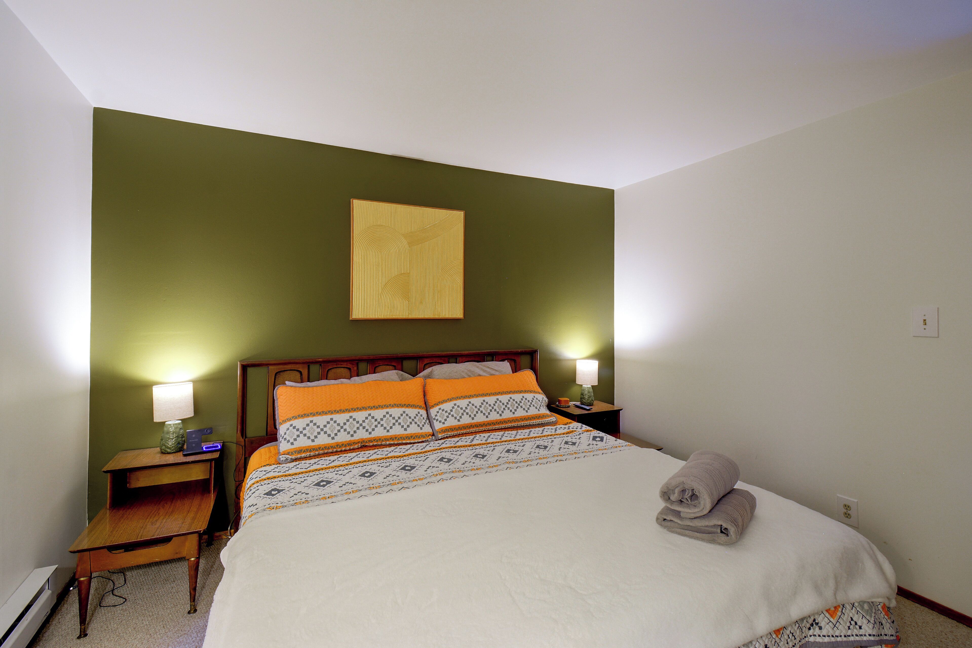 A neatly made bed with patterned bedding, a wooden headboard, and two bedside lamps.