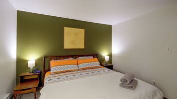 A neatly made bed with patterned bedding, a wooden headboard, and two bedside lamps.