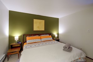 A neatly made bed with patterned bedding, a wooden headboard, and two bedside lamps. - Hood Canal Views & Near Alderbrook Resort! (Union)
