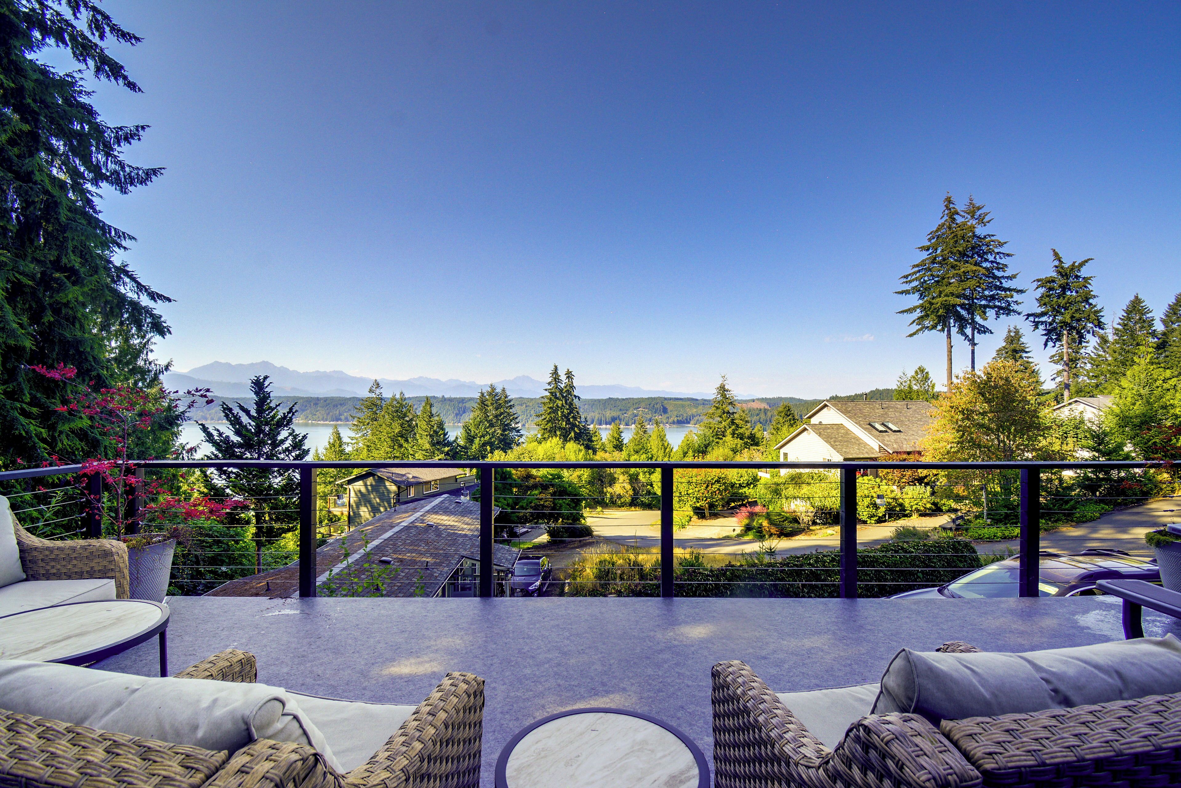 Una terraza con mobiliario exterior, vistas a una zona residencial y una cordillera en la distancia.