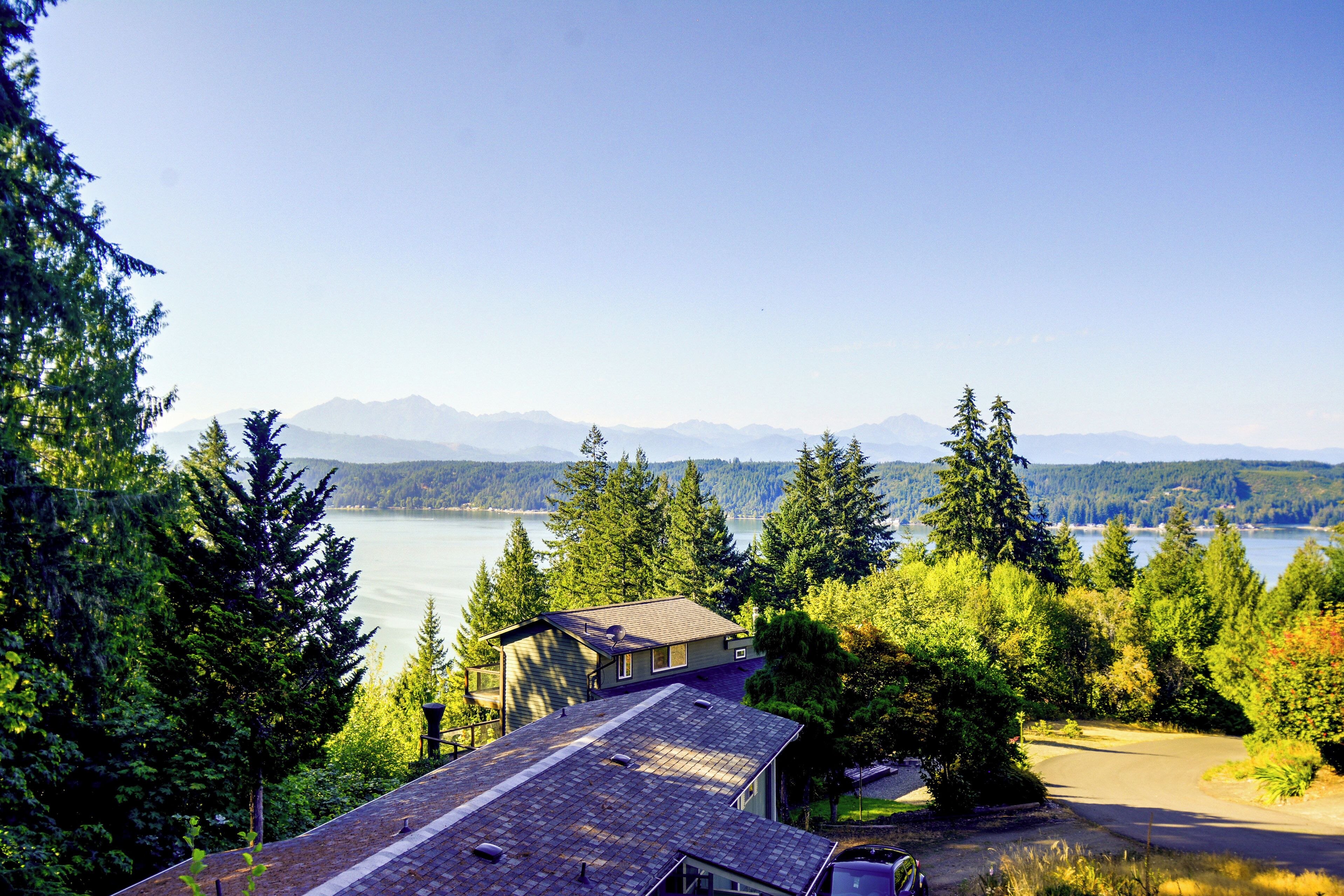 A house with a view of a lake and mountains in the distance.