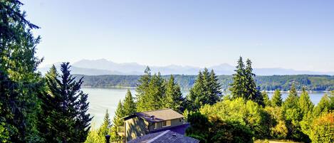 A house with a view of a lake and mountains in the distance.