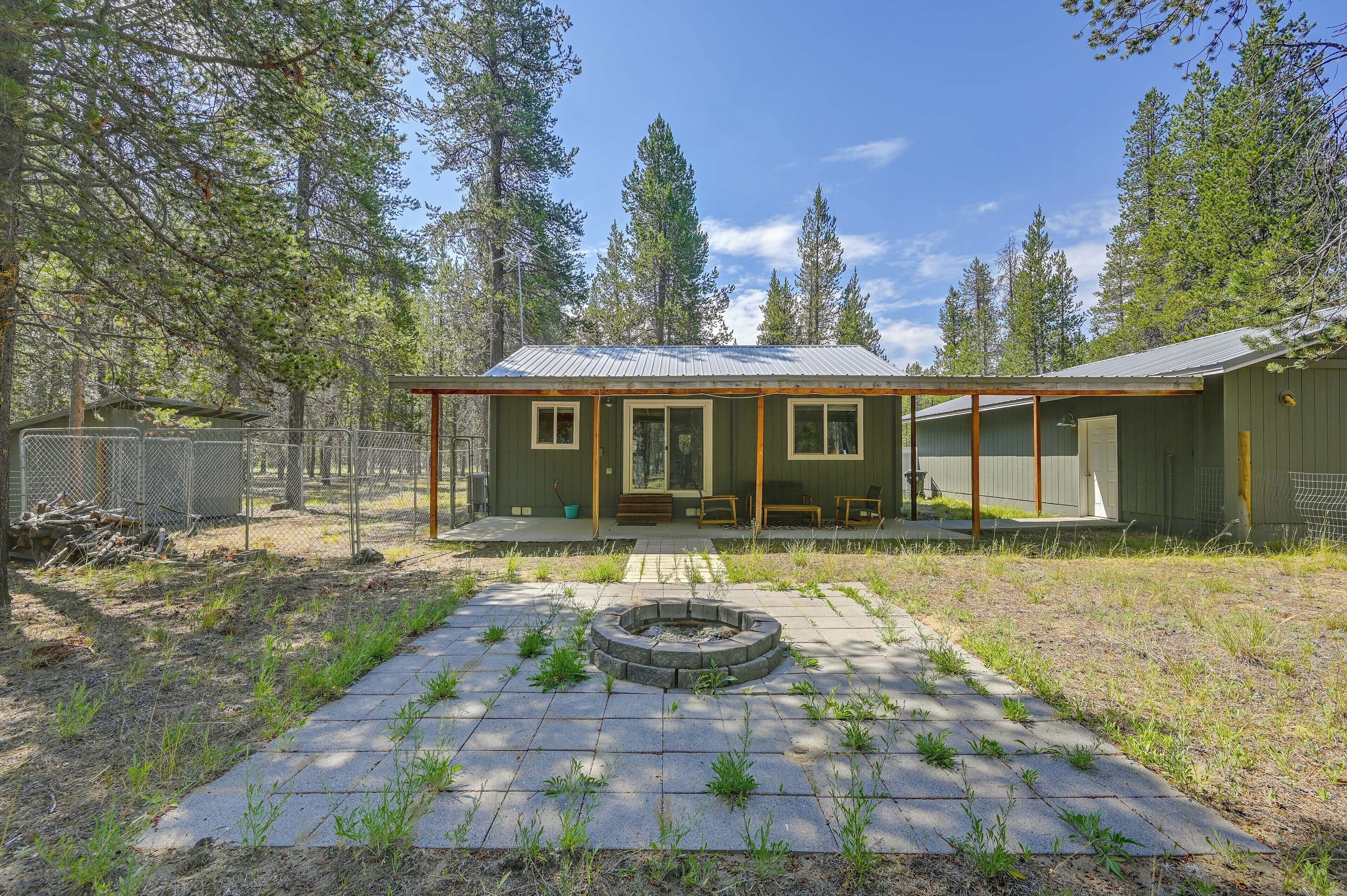 A single-story building with a covered porch, a fire pit in the center, and a fenced yard.