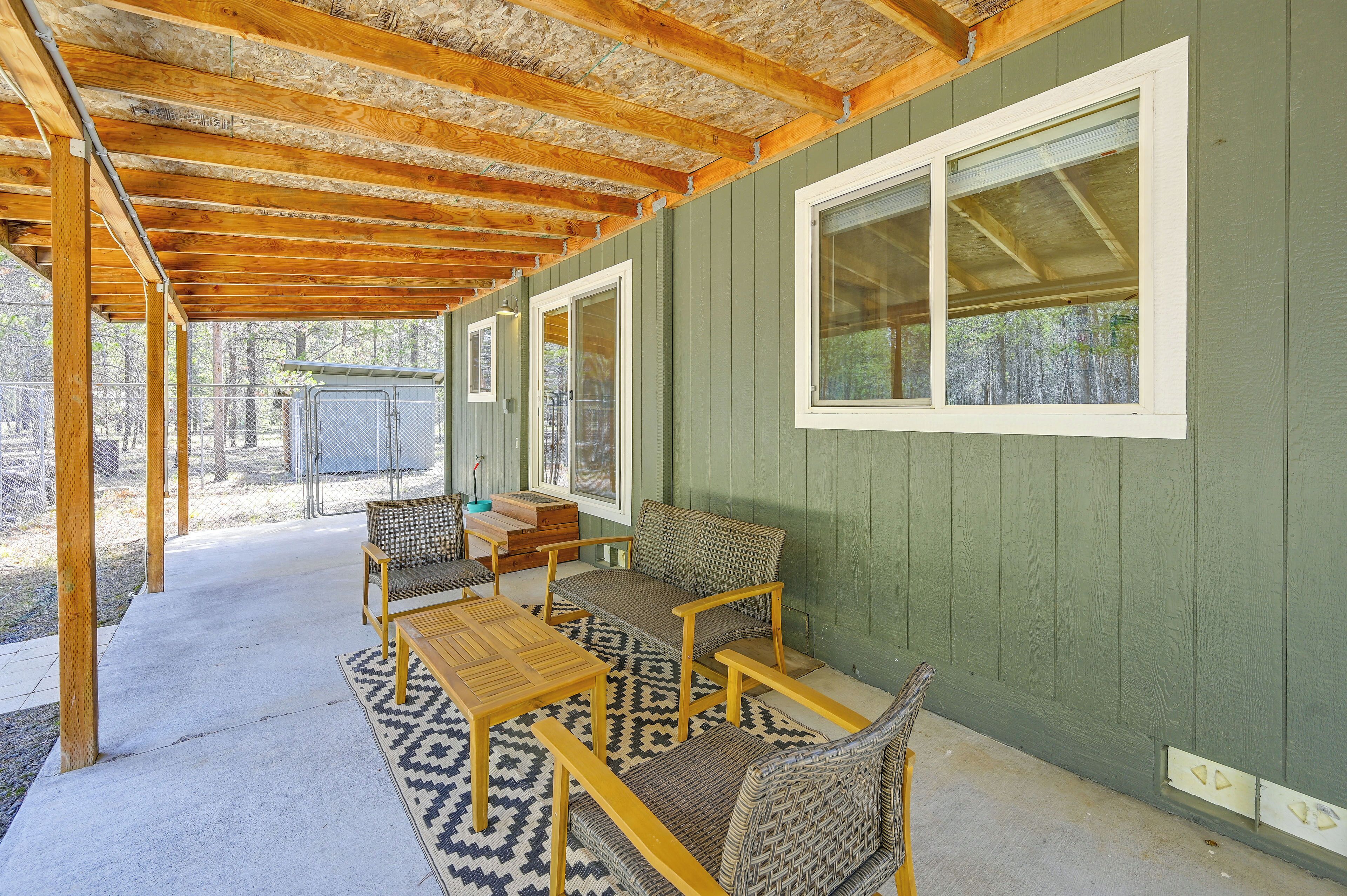 A covered patio area with a wooden table and chairs, a window, and a view of the outdoors.