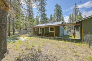 A cabin with a porch, a small deck, and a fenced yard.