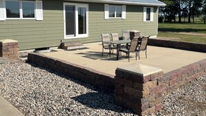 Ein Haus mit Terrasse, Gartenmöbeln und einem Schotterweg.