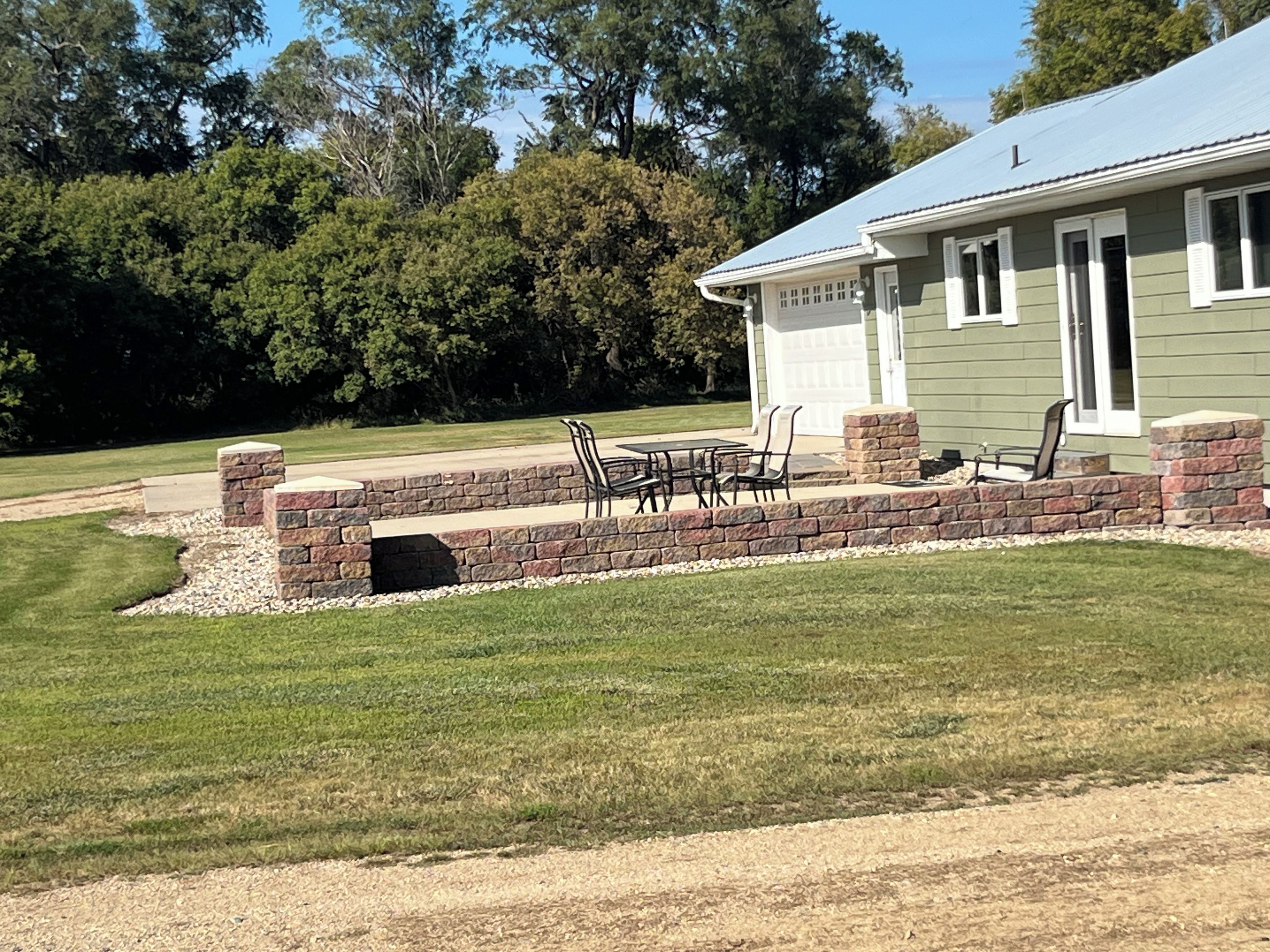 Ein Haus mit einer Terrasse, die mit Gartenmöbeln ausgestattet ist.