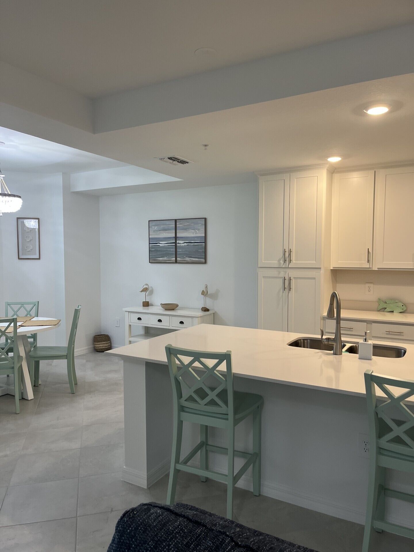 Una cocina moderna con armarios blancos, una isla central con taburetes y un área de comedor con mesa y sillas.