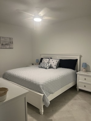A bedroom with a bed, nightstands, a desk, a ceiling fan, and a wall-mounted artwork. - Coastal Feel  Wellen Park G&CC condo (Venice)