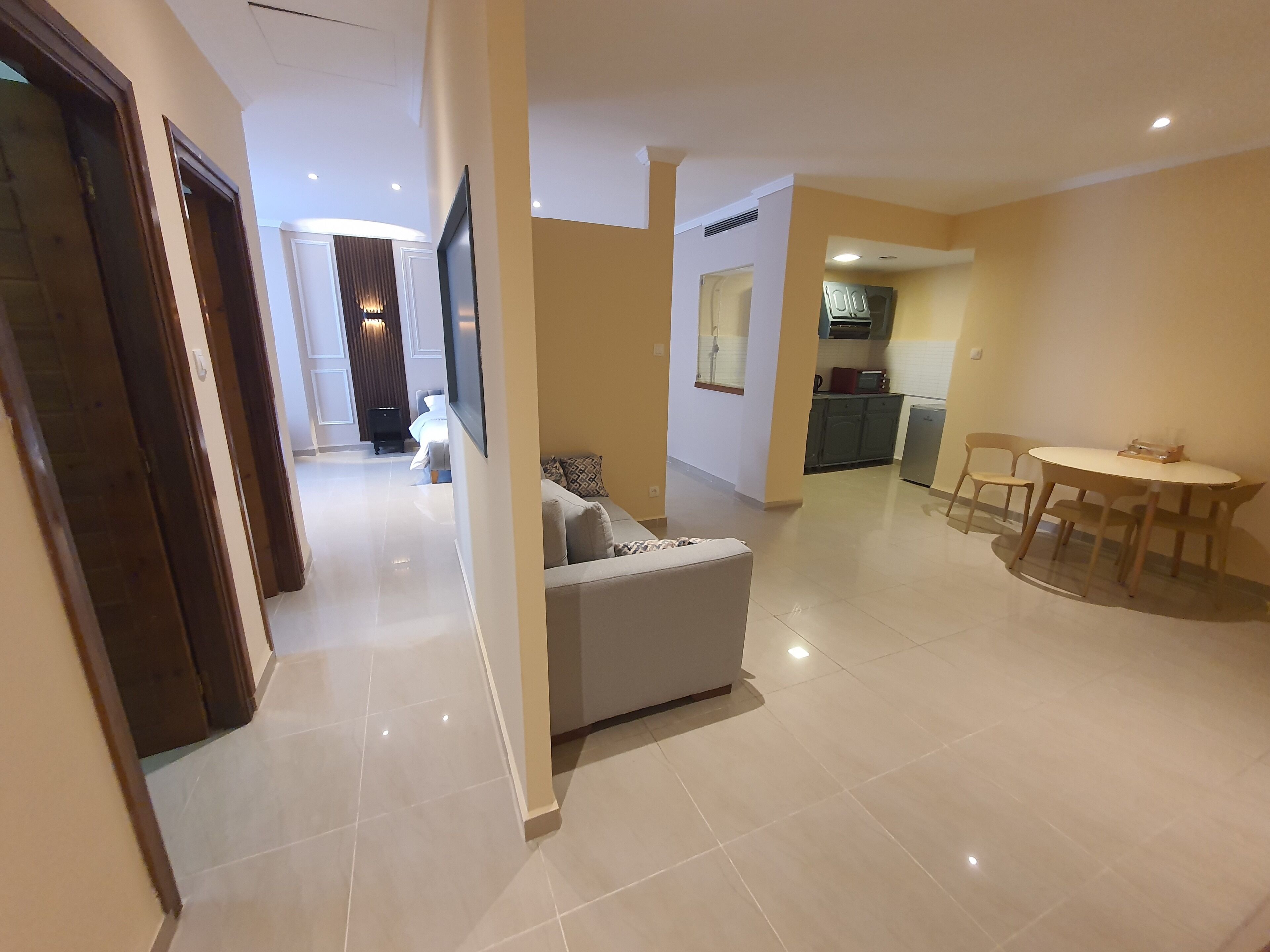 A modern living area with a sofa, a dining table with chairs, and a kitchen in the background.