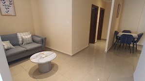 A living room with a sofa, a coffee table, and a dining area with chairs and a table.