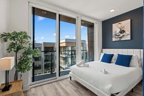Ein modernes Hotelzimmer mit einem großen Bett, Blick auf die Stadt und einem Balkon.