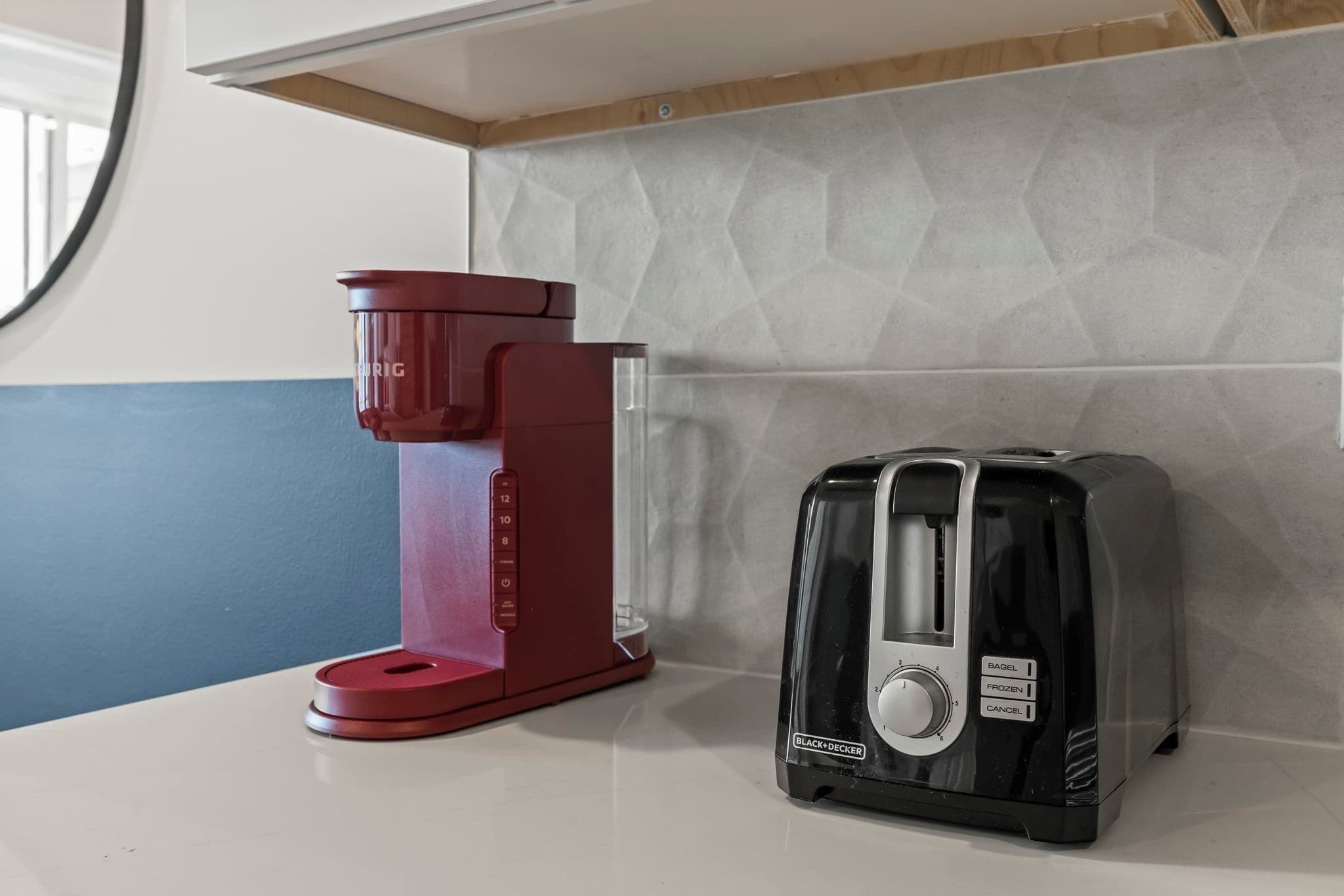 Eine Küchenarbeitsplatte mit einer roten Kaffeemaschine und einem schwarzen Toaster.
