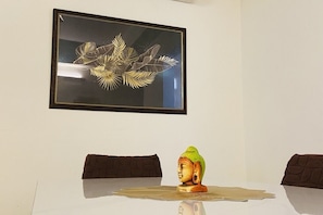 A framed artwork on a wall, a Buddha statue on a table, and a patterned cushion. - Spacious 3-bedroom apartment with AC in cool Gurugram (Gurugram)