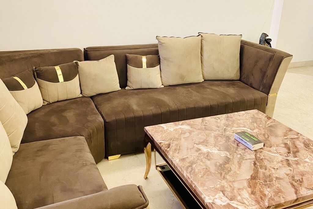 Ein braunes, ledernes Ecksofa mit passenden Kissen und ein Couchtisch aus Marmor mit einem Buch darauf.