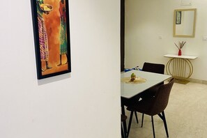 A dining area with a table, chairs, and a wall-mounted mirror. - Spacious 3-bedroom apartment with AC in cool Gurugram (Gurugram)